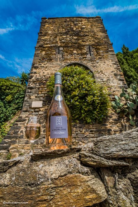 Photographie de la bouteille Tour de l'Horloge rosé, posée sur un muret et en arrière-plan la tour de l'horloge.